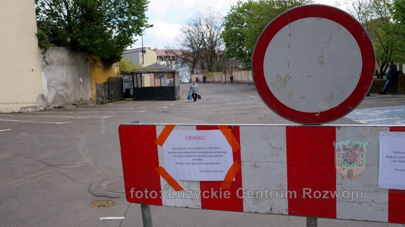 biało-czerwony płotek ze znakiem zakaz ruchu, w tle pusty parking